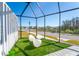Screened in patio with sleek modern white outdoor seating on green artificial turf at 2942 Wordsmith Rd, Kissimmee, FL 34746