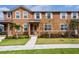 Two story townhome featuring stucco exterior with a well-manicured lawn, sidewalk, and decorative landscaping at 2962 Firebush Way, Clermont, FL 34711