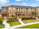 Exterior view of townhomes featuring a manicured lawn and lovely landscaping at 2962 Firebush Way, Clermont, FL 34711