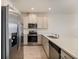 Kitchen featuring stainless steel appliances, white cabinetry, quartz countertops and wood-look tile flooring at 2962 Firebush Way, Clermont, FL 34711