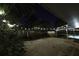 View of a concrete backyard and screened-in pool, enhanced by string lights and featuring lush greenery at 4174 Fallwood Cir, Orlando, FL 32812