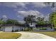 Charming light grey home featuring a spacious driveway and well-manicured lawn with mature trees at 4174 Fallwood Cir, Orlando, FL 32812