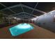 A screened-in pool shimmers with blue light at night, enhanced by string lights and featuring a concrete surround at 4174 Fallwood Cir, Orlando, FL 32812