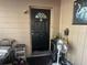Close-up of the front door and porch; a black door with a half-moon window, next to some clutter at 5298 Rose Ave, Orlando, FL 32810