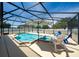 An outdoor, screened pool with a spa, chairs, patio and an umbrella at 654 Chadbury Way, Kissimmee, FL 34744