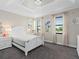 Bright bedroom with a crystal light fixture, gray carpet, and many windows at 10765 Village Lake Rd, Windermere, FL 34786