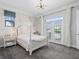 Bright bedroom with a light wood bed frame, bedside tables, and sliding glass doors to a balcony at 10765 Village Lake Rd, Windermere, FL 34786