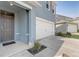 Inviting entryway featuring a white garage door, gray front door, and tidy landscaping at 11279 Amber Ridge Dr, Zellwood, FL 32798