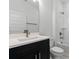 Bathroom with a black vanity, white basin sink, white tile walls and nickel hardware at 13536 Autumn Harvest Ave, Winter Garden, FL 34787