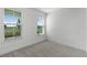 Bedroom with carpet, white walls, white trim, and large windows overlooking a lush landscape at 13536 Autumn Harvest Ave, Winter Garden, FL 34787