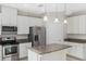 Bright kitchen features stainless steel appliances, granite countertops and a center island with pendant lighting at 14040 Helsby St, Orlando, FL 32832