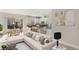 Open-concept living room with a modern sofa, dining area, and kitchen with stainless steel appliances at 14040 Helsby St, Orlando, FL 32832