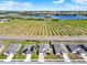 Detailed aerial view of modern homes with well-kept lawns, accentuated by the rows of orchard trees nearby at 1579 Swan Lake Cir, Dundee, FL 33838