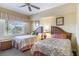 Cozy bedroom with two beds, ceiling fan, and natural light from the window at 1598 Heritage Crossing Ct # 302, Reunion, FL 34747