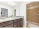 Bathroom featuring granite countertops, dual sinks, dark cabinets, and glass enclosed shower at 1639 Lima W Ave, Kissimmee, FL 34747