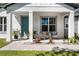 Inviting covered front porch with stylish seating, lush landscaping, and a bright turquoise front door at 1806 Paloma Ave, Sanford, FL 32771