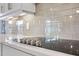 Close up of induction cooktop, light gray subway tile backsplash and white cabinetry at 2011 Soaring Oak Way, Winter Park, FL 32792