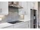 Close-up of modern kitchen featuring gray backsplash, stainless steel range hood and appliances at 2011 Soaring Oak Way, Winter Park, FL 32792