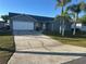 Charming single-story home with a well-maintained lawn, palm trees, and a two-car garage at 214 Magellan Dr, Kissimmee, FL 34758