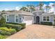 Charming exterior view of a grey home featuring an arched entryway and a brick paver driveway at 231 Cherokee Hill Ct, Deland, FL 32724