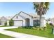 Stylish single-story home with a manicured lawn and a white exterior and a neatly trimmed palm tree at 2430 Sanderling St, Haines City, FL 33844