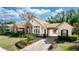 A side view of a single-story home featuring stone accents, a tile roof, a porte-cochere and driveway at 25813 Feather Ridge Ln, Sorrento, FL 32776