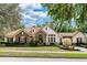 Charming single-story home featuring stone accents, a tile roof, and a well-manicured front lawn and landscaping at 25813 Feather Ridge Ln, Sorrento, FL 32776