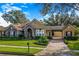 Charming single-story home featuring stone accents, porte-cochere, manicured landscaping, and brick paved driveway at 25813 Feather Ridge Ln, Sorrento, FL 32776