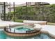 Close-up of in-ground pool hot tub with waterfall feature and lush landscaping behind screening at 25813 Feather Ridge Ln, Sorrento, FL 32776