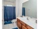 Bathroom with wood vanity, large mirror, tile floor, shower and tub combo with blue shower curtain at 2659 Calistoga Ave, Kissimmee, FL 34741