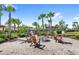 Cozy outdoor fire pit surrounded by seating, nestled among lush landscaping and mature palm trees at 2694 Giardino Loop, Kissimmee, FL 34741