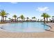 Large community pool with a round walk-in portion with palm trees and lounge chairs at 2694 Giardino Loop, Kissimmee, FL 34741