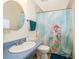 Traditional bathroom with a blue vanity, round mirror, and a shower with a hummingbird patterned curtain at 38851 Forest Dr, Eustis, FL 32736
