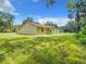 Expansive backyard featuring a home with a covered patio, green grass, and mature trees at 509 Mulberry St, Fruitland Park, FL 34731