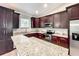 Modern kitchen with dark wood cabinets, stainless steel appliances, and expansive granite countertops at 509 Mulberry St, Fruitland Park, FL 34731