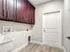 Functional laundry room featuring wood-look flooring, storage cabinets and a utility sink at 509 Mulberry St, Fruitland Park, FL 34731