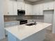 Bright kitchen with white cabinetry, stainless steel appliances, island with quartz countertop, and subway tile backsplash at 618 Duke Dr, Haines City, FL 33844