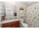 Cozy bathroom with wood vanity, shower with floral curtain, and ample lighting at 9210 Sw 60Th Court Rd, Ocala, FL 34476