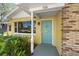 Close-up of the home's entrance with a teal door, yellow siding, and brick accents at 926 Mayfair Cir, Orlando, FL 32803
