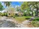 Lovely single-story home with yellow siding, a teal door, mature trees, and a well-maintained lawn at 926 Mayfair Cir, Orlando, FL 32803