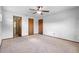 View of a spacious main bedroom with neutral carpet, ceiling fan, and three interior doors at 947 N Atmore Cir, Deltona, FL 32725