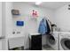 Laundry room with washer, dryer, utility sink, storage shelves, and tile floor at 1056 Royal Saint George Dr, Orlando, FL 32828
