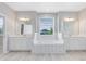 Bright primary bathroom with a soaking tub between two vanities, with a view of the backyard at 2661 Estuary Loop, Oviedo, FL 32765