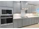 Modern kitchen featuring stainless steel appliances, gray cabinetry, white countertops, and subway tile backsplash at 12805 Charmed Dr, Winter Garden, FL 34787