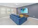Comfortable living room featuring a blue sectional sofa, large screen TV, and natural light from multiple windows at 12805 Charmed Dr, Winter Garden, FL 34787