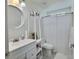 Bright bathroom featuring a circular mirror and a shower with white shower curtain at 1309 Rebecca Dr, Haines City, FL 33844