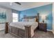 Bedroom featuring a wooden bed frame, blue accent wall, and a window with curtains at 1628 Moon Valley Dr, Davenport, FL 33896