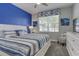 Bright bedroom featuring a white bed frame, blue accent wall, and a window with blue accents at 1628 Moon Valley Dr, Davenport, FL 33896