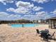 A community pool with ample lounge chairs and tables, with neighborhood homes in the background at 1721 Teagan Ln, Winter Haven, FL 33884