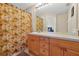 Functional bathroom with a palm-themed shower curtain, wood cabinets, and a large mirror at 2355 Silver Palm Dr, Kissimmee, FL 34747